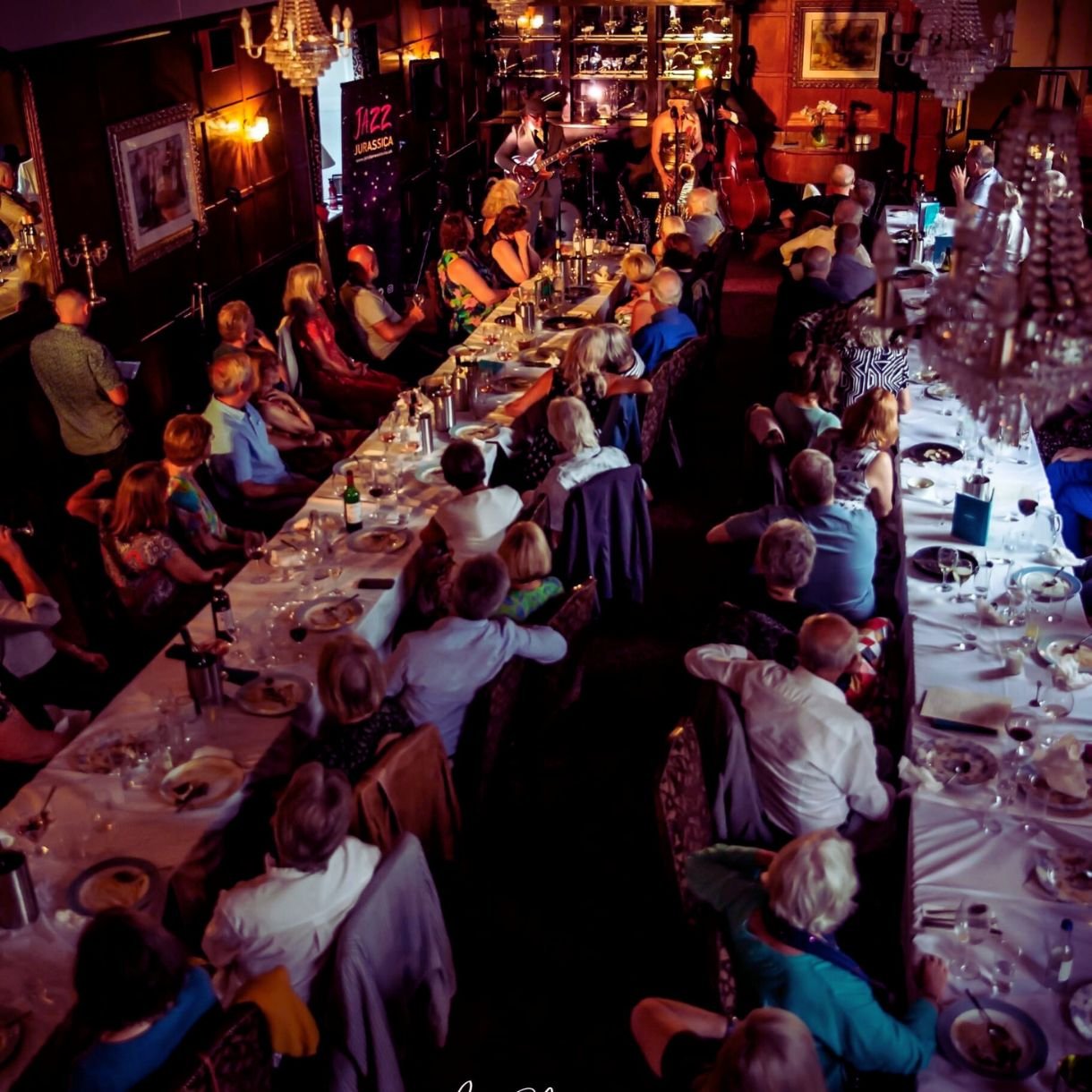 Long shot overlooking jazz band playing to audience at tables