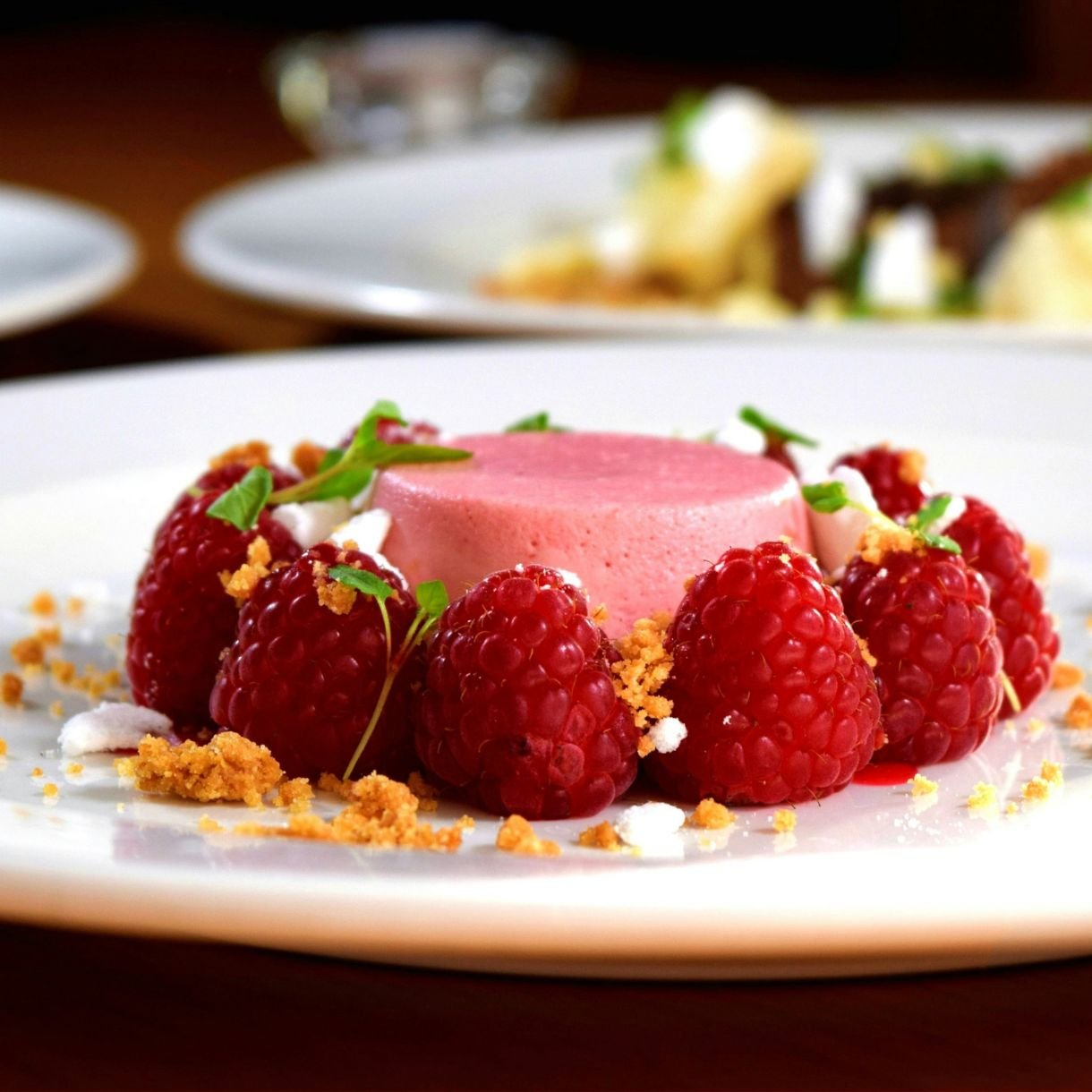 Strawberry pudding edged with rapsberries on a white plate