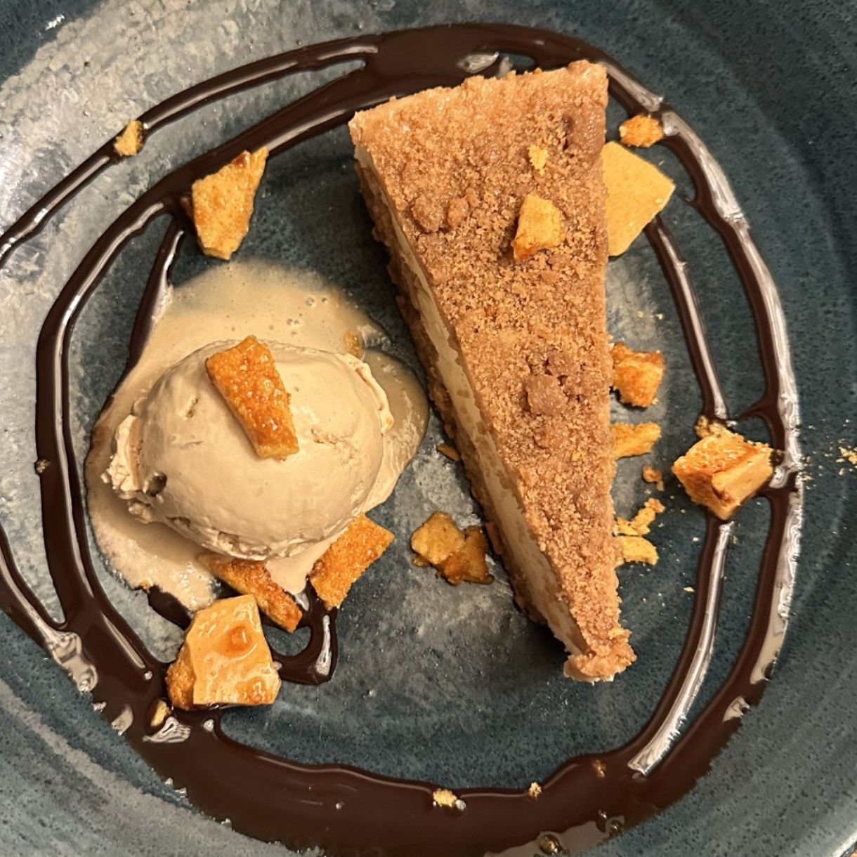 Caramel cheesecake with ice cream on a black plate