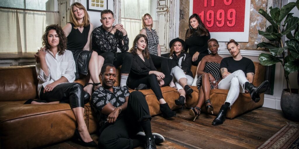 Group of young adults sitting on sofa looking into camera