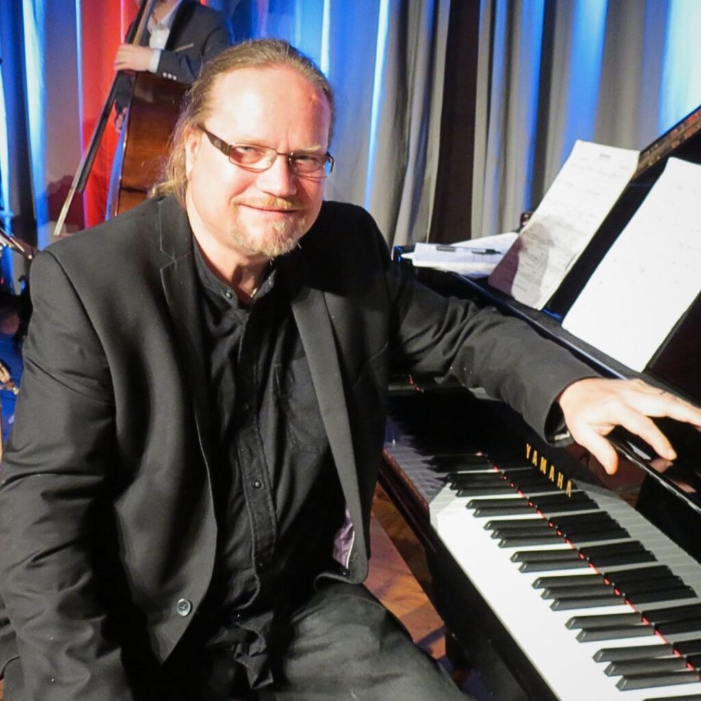 Craig Milverton facing towards camera sitting at piano