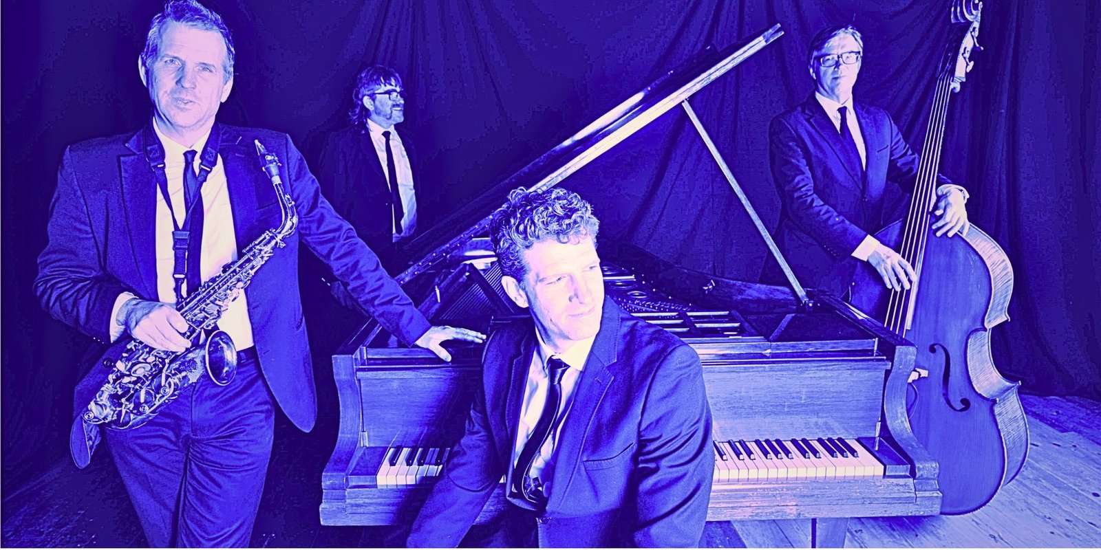 Jazz quartet posed around a grand piano under purple lighting, featuring saxophone, double bass and piano players in dark suits.