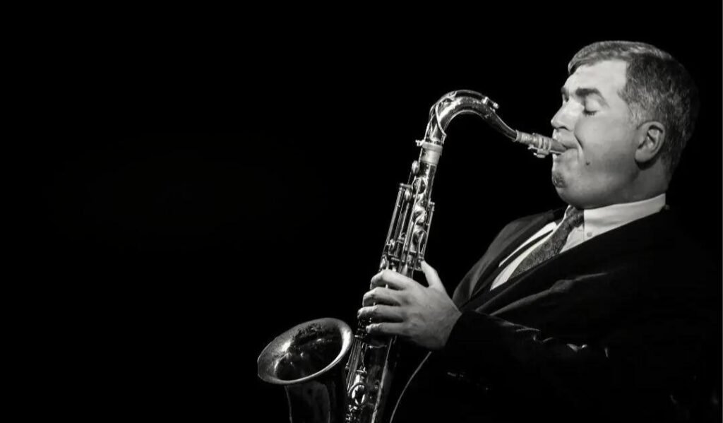 Black and white profile image of Simon Spillett playing tenor saxophone during an energetic live jazz performance.