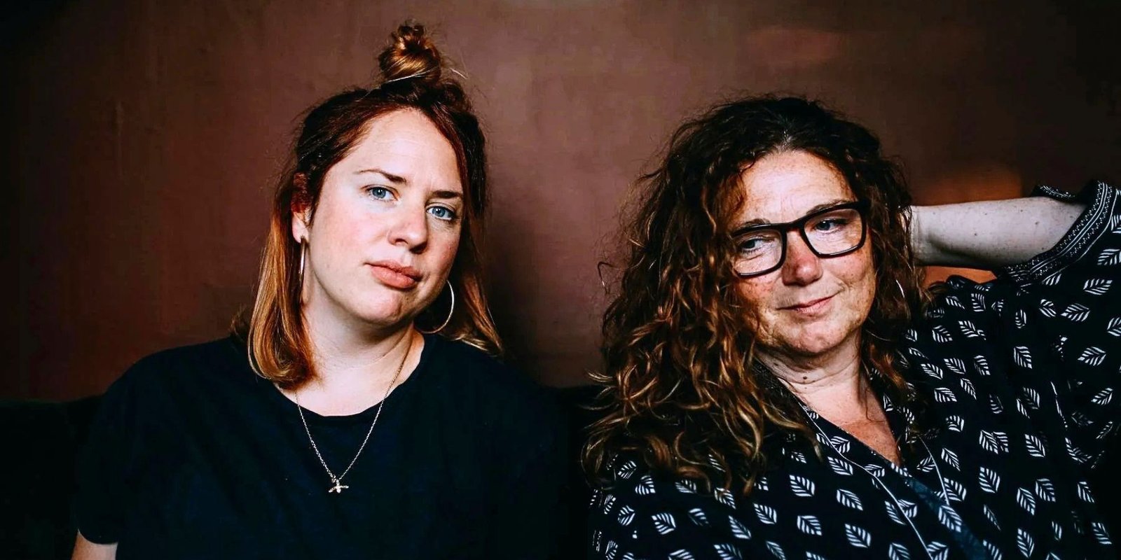Two women, one long-haired redhead, Rebecca Nash, the other long curly dark hair, Sara Colman facing on camera